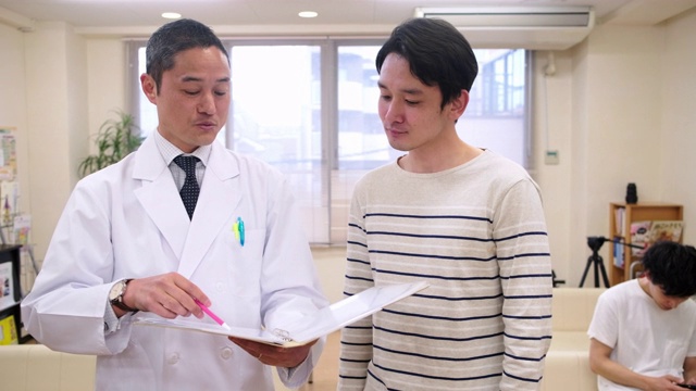 微笑的日本男医生安抚男性病人视频素材画面3