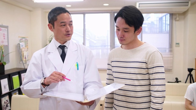 微笑的日本男医生安抚男性病人视频素材画面4
