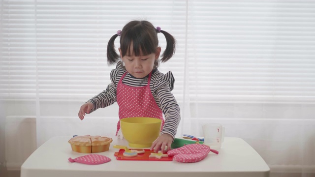 蹒跚学步的小女孩假装玩准备食物的游戏视频素材