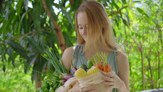 年轻女子把几种蔬菜放在一个可重复使用的袋子里。减少塑料污染的概念。减少和重用视频素材