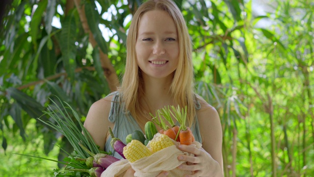 年轻女子把几种蔬菜放在一个可重复使用的袋子里。减少塑料污染的概念。减少和重用视频素材