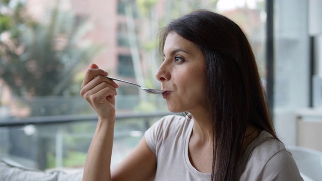 一个漂亮女人在家里吃着一碗麦片的特写视频素材