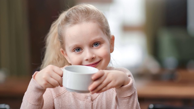 可爱的小女孩的脸拿着茶杯摆姿势在咖啡馆玩。近距离拍摄4k红色相机视频素材