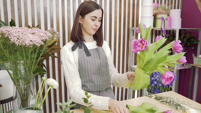 年轻女子花匠正在花店或花房里制作一束郁金香视频素材