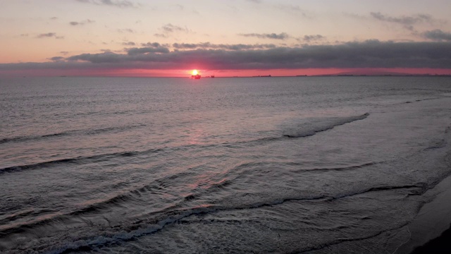 在洛杉矶亨廷顿海滩附近的南加州海岸的太平洋上，一个近海石油和天然气水力压裂钻井平台的日落镜头视频素材