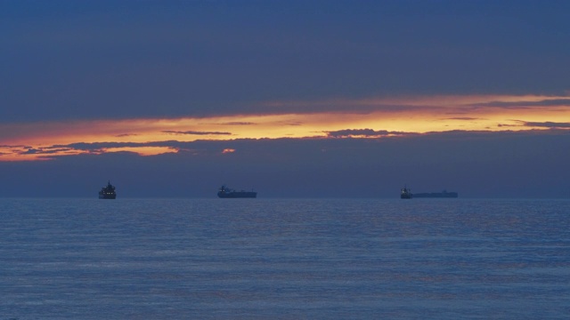 树木货运船在夕阳的余晖中漂浮在海上。视频素材