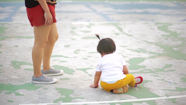 亚洲婴儿和他妈妈坐在篮球地板上。视频素材