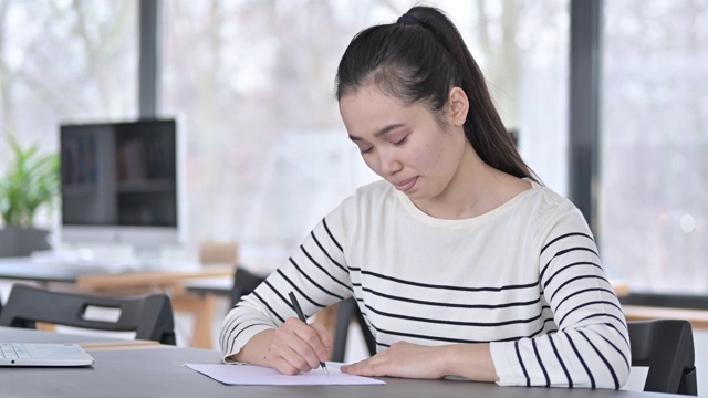 年轻漂亮的亚洲女人在办公室做文书工作视频素材画面1