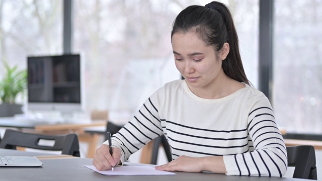 年轻漂亮的亚洲女人在办公室做文书工作视频素材画面3
