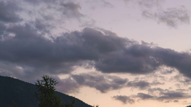 下午/晚上的天空和缓慢移动的云在山上和树的时间推移视频素材