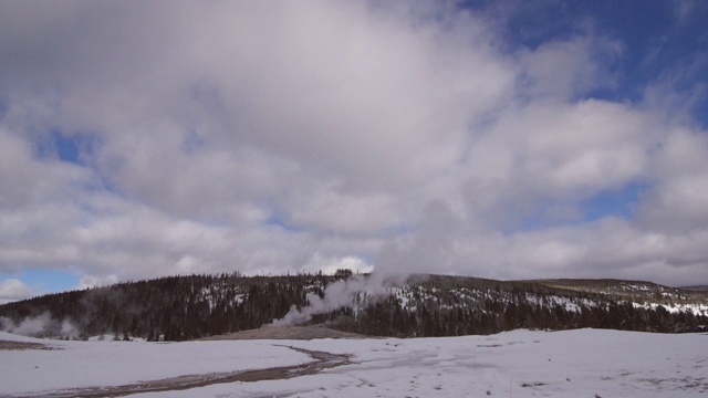 老忠实间歇泉释放烟雾包围的雪，蒸汽在国家公园反对多云的天空在冬天-黄石，怀俄明州视频素材