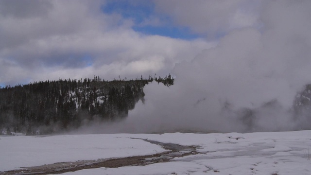 老忠实喷泉喷出烟雾包围的雪对天空，蒸汽在国家公园在冬季爆发-黄石，怀俄明州视频素材