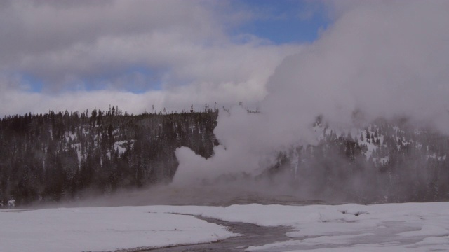 老忠实喷泉喷出蒸汽周围的雪对天空，蒸汽在国家公园在冬季发射-黄石，怀俄明州视频素材