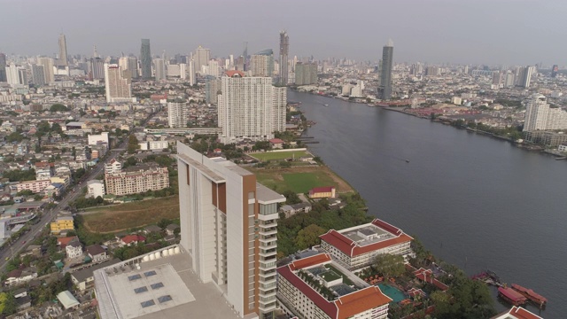 空中拍摄的河流在城市建筑与天空，无人机向后飞行城市景观-曼谷，泰国视频素材