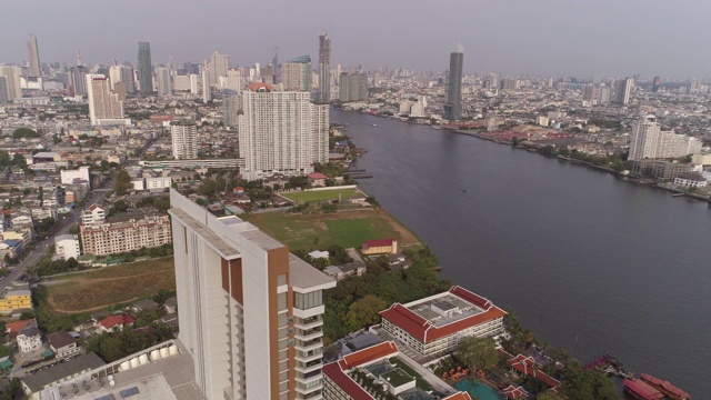 空中拍摄的河流在城市的建筑物对天空，无人机上升的城市景观-曼谷，泰国视频素材