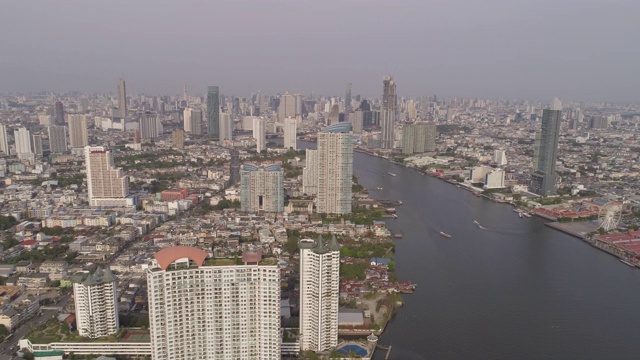 航拍河上的船只在城市的建筑物对天空，无人机向后飞行城市景观在阳光明媚的一天-曼谷，泰国视频素材