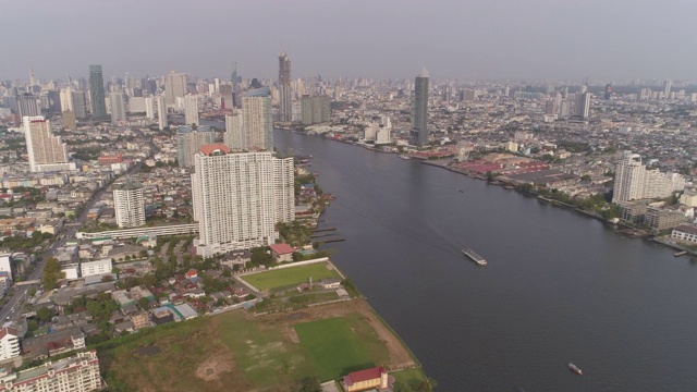 空中拍摄的河流在城市的建筑物对天空，无人机向前飞行的城市景观-曼谷，泰国视频素材