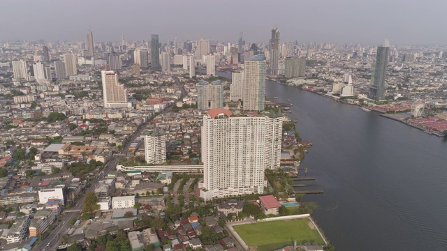 空中拍摄的河流在城市的建筑物在晴朗的一天，无人机向前飞行的城市景观对天空-曼谷，泰国视频素材