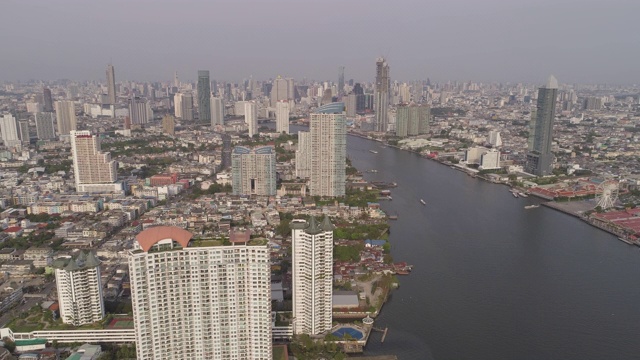 航拍的河上的船只在城市的建筑物对天空，无人机向前飞行的城市景观在阳光明媚的一天-曼谷，泰国视频素材