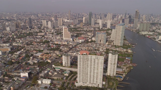 航拍的城市景观与河上的船只对天空，无人机平移在城市的建筑物在晴朗的一天-曼谷，泰国视频素材