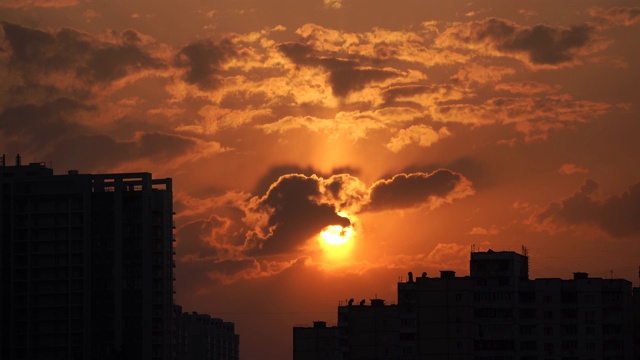 城市剪影与一个戏剧性的日落橙色云和太阳圆盘视频素材