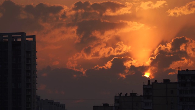 城市剪影与一个戏剧性的日落橙色云和太阳圆盘视频素材