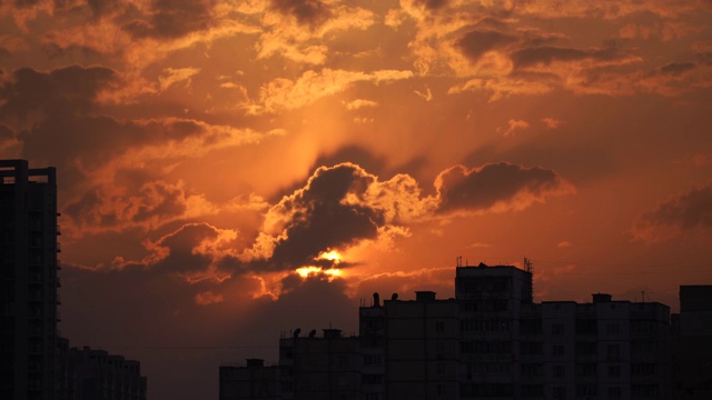 城市剪影与一个戏剧性的日落橙色云和太阳圆盘视频素材