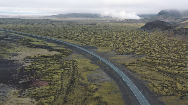 航拍显示，一辆汽车驾驶在道路上跨越火山景观，冰岛视频素材