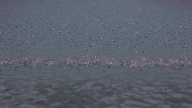 雨滴落在池塘、湖泊、河流的水面上。在暴风雨中，大雨滴落在水坑里。大雨落下背景。水滴落在液体表面视频素材