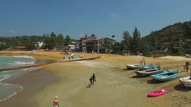 在阳光明媚的一天，无人机在海面上向前飞行，斯里兰卡阿鲁甘湾上空的空中拍摄的人们视频素材