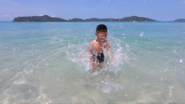 亚洲孩子在夏天的海水中戏水，慢动作，快乐的孩子在海里玩耍视频素材