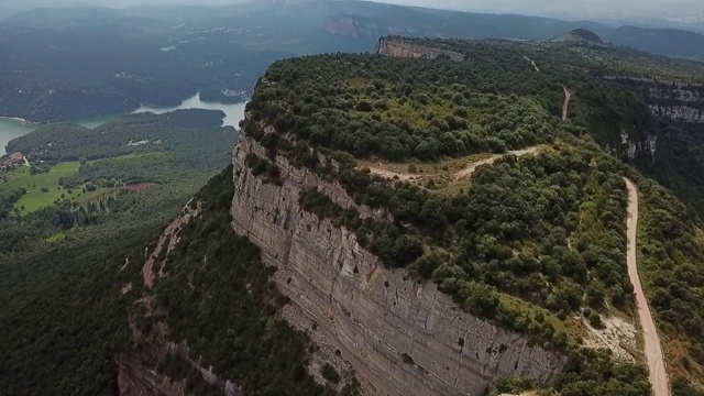 空中倾斜拍摄的岩石山附近的河流对多云的天空，无人机飞过自然的绿色景观在晴朗的一天-塔弗泰，西班牙视频素材