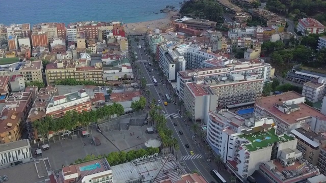 航拍在城市建筑中街道上的车辆，无人机飞向海滩-西班牙视频素材