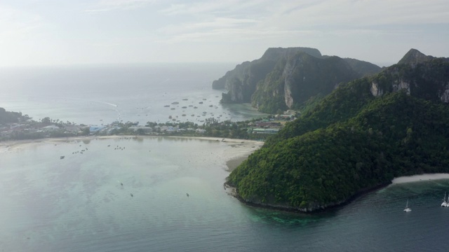 空中平移拍摄的船只在海上对绿色的山脉，无人机飞过海岸线对天空-皮皮岛，泰国视频素材