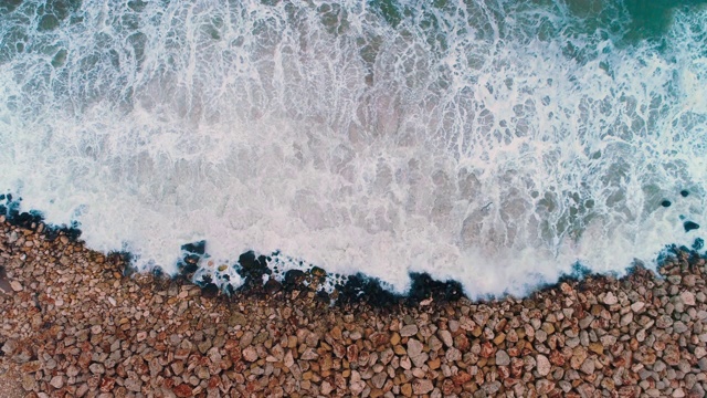 海浪撞击海滩岩石的鸟瞰图视频素材