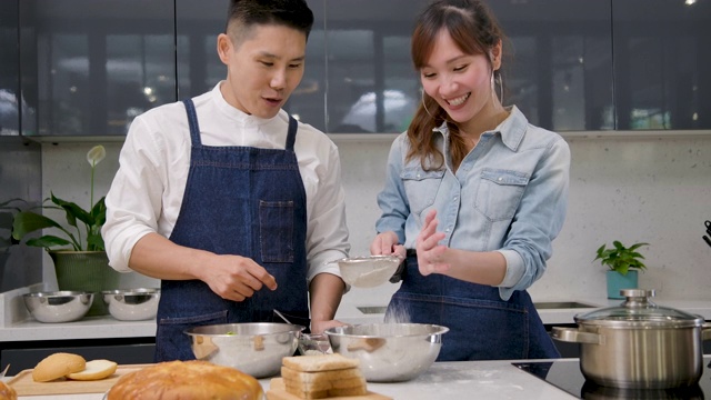 年轻的亚洲夫妇在厨房里摆桌子准备早餐时，又跳又唱。视频素材