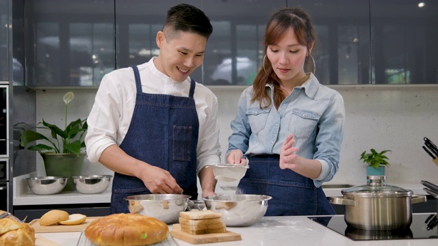 年轻的亚洲夫妇在厨房里摆桌子准备早餐时，又跳又唱。视频素材