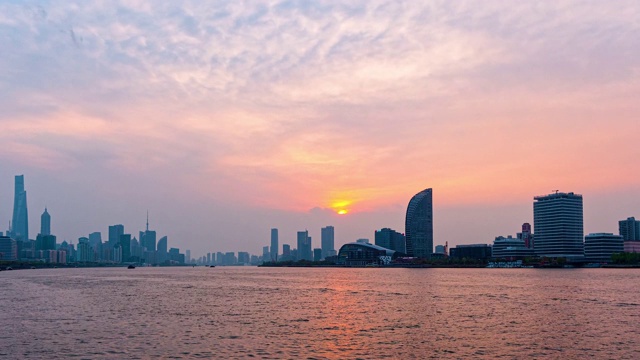 时间流逝的镜头在上海城市日落与外滩天际线和黄浦江的背景，货船在河上航行，从日落到蓝色小时，4k视频，b卷拍摄。视频素材