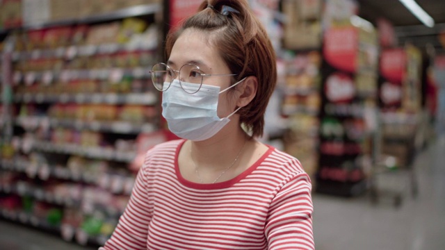 亚洲女孩在超市购物与面罩保护视频素材