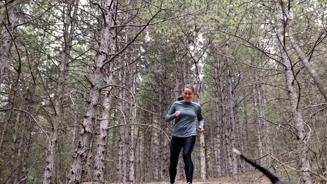 在寒冷的秋日，勤奋的健身女子在森林里慢跑视频素材