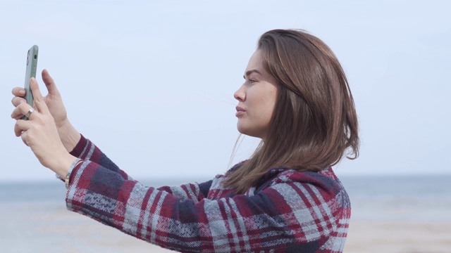 自信的黑发女孩在户外自拍。侧面的年轻的黑发女子摆姿势在河岸和微笑。快乐，生活方式，千禧一代，休闲，自然。视频素材