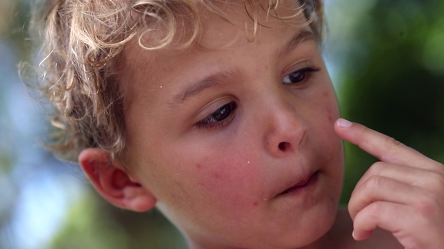 可爱的幼儿脸肖像触摸脸与手指。孩子集中在外面人像视频素材