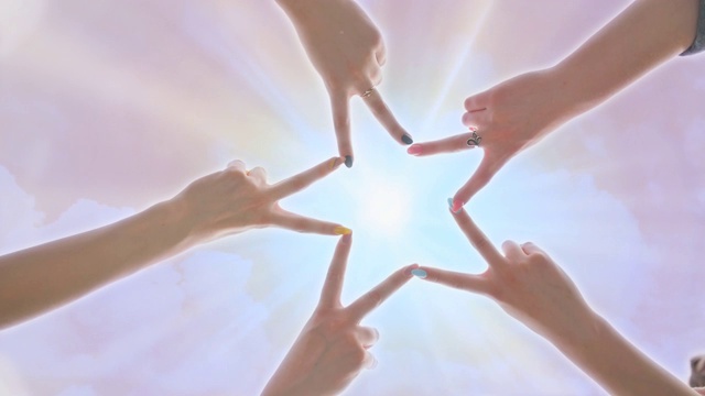 在耀眼的阳光下，人们用手指在粉红色神奇的天空下形成星星的形状视频素材画面2
