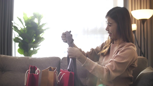 美丽的亚洲女人在家里收到一个包裹和打开购物袋非常高兴视频素材