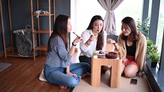 一位年轻美丽的亚洲华裔女士在她的公寓和朋友一起庆祝她的生日，一起吃生日蛋糕视频素材