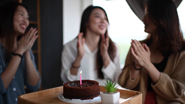 一位年轻美丽的亚洲华裔女士在她的公寓和朋友一起庆祝她的生日，一起吃生日蛋糕视频素材