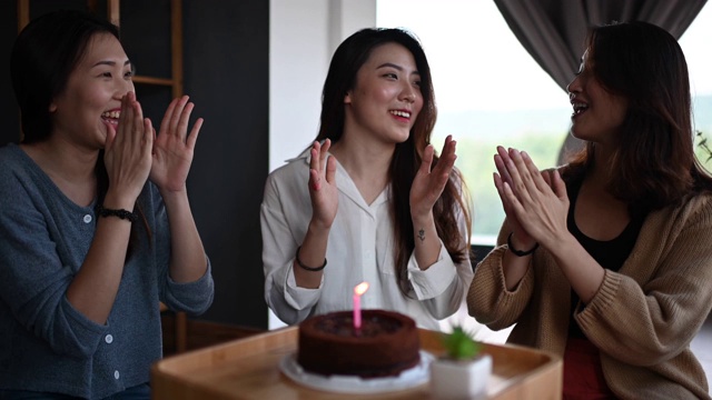 一位年轻美丽的亚洲华裔女士在她的公寓和朋友一起庆祝她的生日，一起吃生日蛋糕视频素材