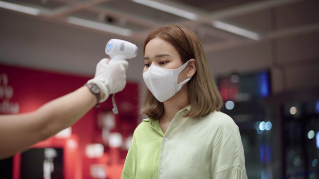 耐心的亚洲妇女用体温计测量脸部和手部的温度视频素材