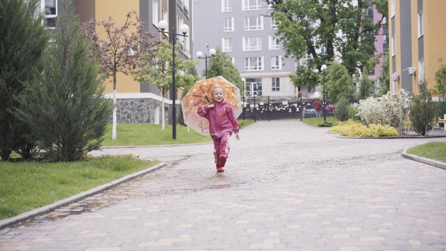 可爱快乐的金发女孩跳着跑着拿着伞去拍照。欢快的白人孩子的肖像在春天或夏天的雨天在粉红色的衣服有乐趣。欢乐、乐趣、休闲、童年。视频素材