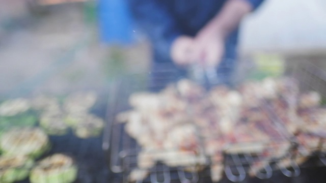 在花园里烧烤。烤鸡肉和蔬菜。摄像机在烤架上移动视频素材